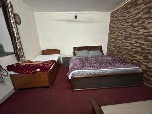a bedroom with two beds and a brick wall at Mussoorie Lodge in Mussoorie