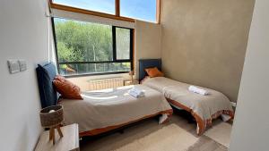 two beds in a small room with a window at Cabañas Indómita in El Bolsón