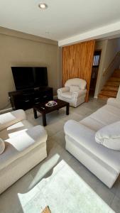 a living room with white furniture and a flat screen tv at Cabañas Indómita in El Bolsón