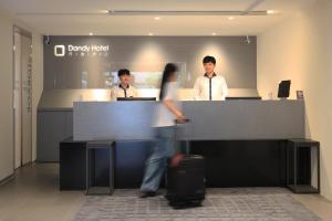 three people standing at a counter with a woman with a suitcase at Dandy Hotel - Tianmu Branch in Taipei
