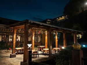 a wooden pavilion with tables and chairs at night at Yangkhil Resort in Tongsa