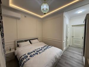 a bedroom with a large white bed with a chandelier at Ayvon Guesthouse in Samarkand