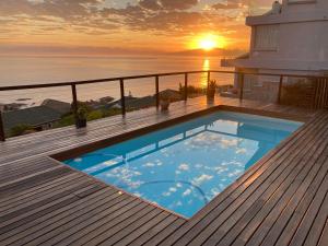 a swimming pool on the deck of a house with the sunset at Oceans Drift Guest House & Self Catering in Simonʼs Town