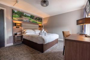 a hotel room with a large bed and a desk at Riverside Hotel in Cirencester