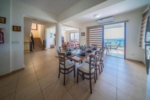 a dining room with a table and chairs and a balcony at Infinity Blue Villa w Pool in Pomos