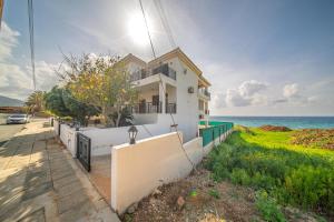a white house with the ocean in the background at Infinity Blue Villa w Pool in Pomos