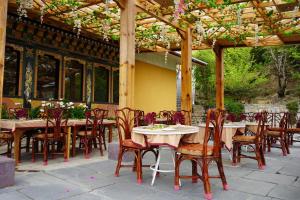 an outdoor dining area with tables and chairs under a pergola at Yangkhil Resort in Tongsa