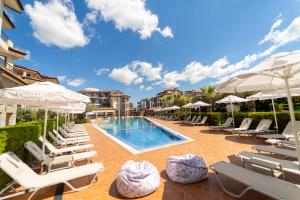 a swimming pool with lounge chairs and umbrellas at Burgas Beach Resort Apartments in Burgas