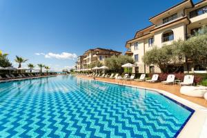 a large swimming pool with chairs and buildings at Burgas Beach Resort Apartments in Burgas