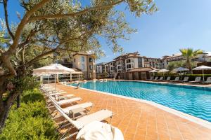 a pool with lounge chairs and umbrellas at a resort at Burgas Beach Resort Apartments in Burgas