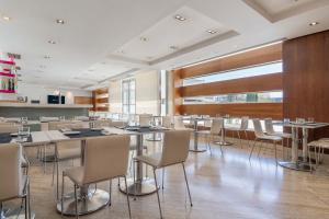 una sala da pranzo con tavoli e sedie bianche di Eurostars i-hotel Madrid a Pozuelo de Alarcón