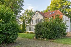 an old house with bushes in front of it at Historisches Landhaus mit Outdoor-Sauna in Ostenfeld