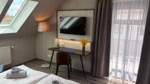 a room with a desk and a tv on the wall at Ryck-Hotel Garni in Greifswald
