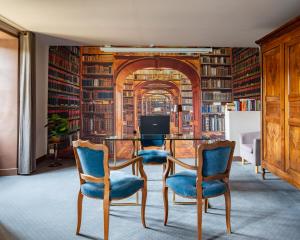 a library with a table and chairs and books at Le Cro-Magnon - hôtel - piscine - climatisation in Les Eyzies-de-Tayac