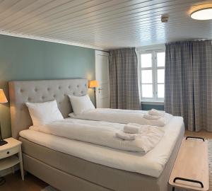 a bedroom with a large bed with white pillows at Lillesand Hotel Norge in Lillesand