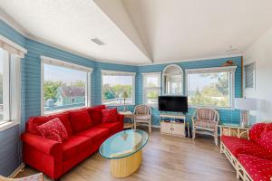 a living room with a red couch and a tv at Pelican Perch in Duck