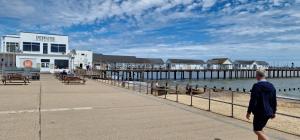 a man walking down a sidewalk next to a pier at Harbour View Penthouse in Lowestoft