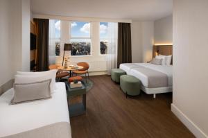 a hotel room with two beds and a table at NH City Centre Amsterdam in Amsterdam