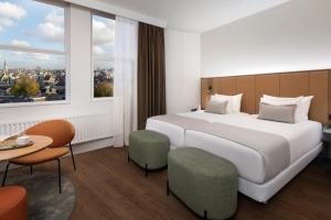 a hotel room with a large bed and a table at NH City Centre Amsterdam in Amsterdam