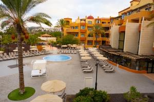 a resort with chairs and umbrellas and a swimming pool at Grand Muthu Golf Plaza Hotel & Spa in San Miguel de Abona