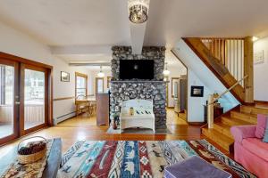 a living room with a stone fireplace with a tv at Wildberry Cottage in Bomoseen