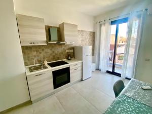 a kitchen with white cabinets and a sink and a window at Rooms Domu Ajo in Monserrato