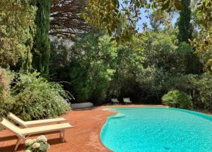 a swimming pool with two chairs and a bench at La mandarine in Ramatuelle