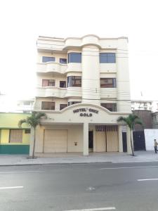 een groot wit gebouw met palmbomen ervoor bij Hotel Onix Gold in Guayaquil