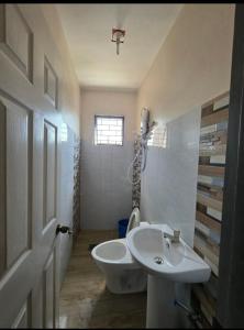 a white bathroom with a sink and a toilet at Rweydz Guest Inn Dorm in Tagbilaran City