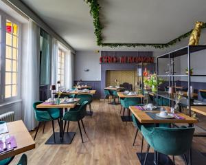 a restaurant with wooden tables and green chairs at Le Cro-Magnon - hôtel - piscine - climatisation in Les Eyzies-de-Tayac