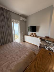 a bedroom with a bed and a desk and a television at Beachfront Apartment Saranda in Sarandë