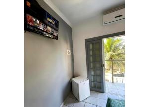 a room with a television on the wall and a door at GrandMaré Hotel in Peruíbe