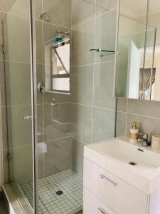 a bathroom with a shower with a sink and a mirror at The Bridge at Montego in Fourways +17 photos