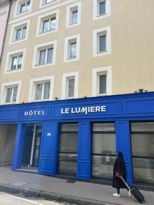 a woman walking in front of a hotel with her luggage at Hotel Le Lumière in Lyon