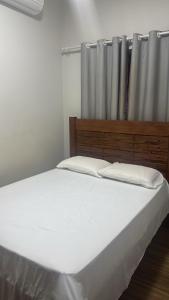 a bedroom with a white bed with a wooden headboard at Pousada e Hotel Mirasol in Mato Verde