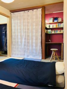a bedroom with a bed and a window with a stool at 旅の宿 もはち Private Guesthouse MOHACHI in Tsuruoka
