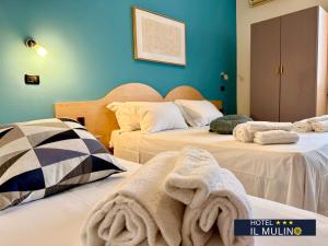 two beds with towels on them in a room at Hotel IL MULINO - Colazione a Buffet e Parcheggio Privato in Casalgrande