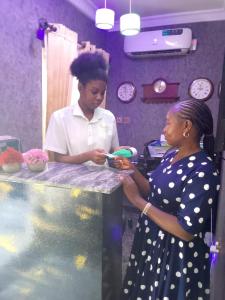 two women standing at a counter looking at a cell phone at Vintage classic suits in Lagos