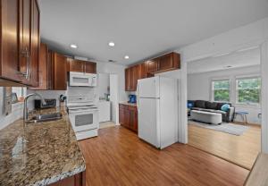 a kitchen with wooden cabinets and a white refrigerator at Central OBX Getaway with Pool and Sound Access in Nags Head
