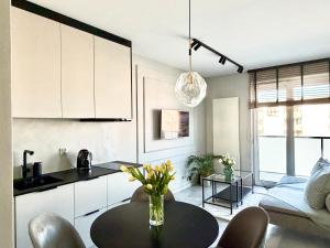 a kitchen and living room with a table with flowers on it at Apartamant Oaza II in Koszalin