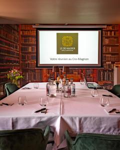 a conference room with a table with a projection screen at Le Cro-Magnon - hôtel - piscine - climatisation in Les Eyzies-de-Tayac +187 photos