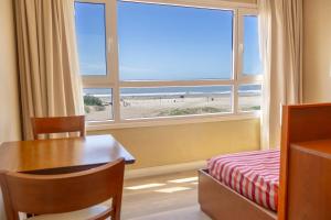 ein Schlafzimmer mit Tisch und Fenster mit Blick auf den Strand in der Unterkunft Sul Mare Hotel in Valeria del Mar