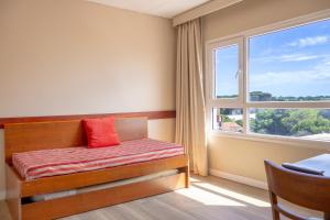 ein Schlafzimmer mit einem Bett mit rotem Kissen und einem Fenster in der Unterkunft Sul Mare Hotel in Valeria del Mar + 28 Fotos