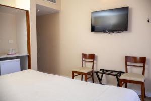 ein Schlafzimmer mit zwei Stühlen und einem Fernseher an der Wand in der Unterkunft Sul Mare Hotel in Valeria del Mar