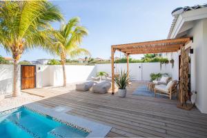 a patio with a swimming pool and a wooden deck at Villa CuraNova in Jan Thiel