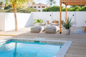 a backyard with a swimming pool and a wooden deck at Villa CuraNova in Jan Thiel