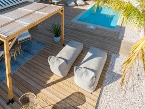 a wooden deck with pillows and a swimming pool at Villa CuraNova in Jan Thiel +16 photos