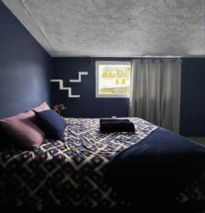 a bedroom with a bed with blue walls and a window at Hospedajes Alta Terra in Quetzaltenango