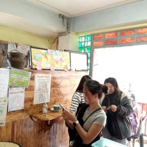a group of women standing around a counter looking at their cell phones at grandmas homestay in Sagada
