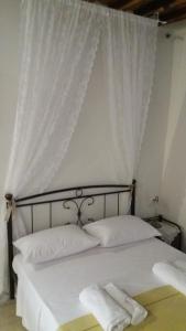 a bedroom with a bed with white curtains at Studio Katerina in Kimolos